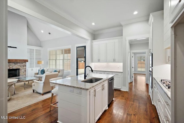 kitchen with sink, white cabinetry, dark hardwood / wood-style floors, light stone countertops, and a center island with sink