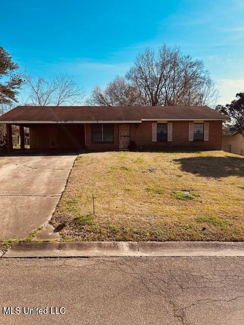 ranch-style house with driveway, an attached carport, and a front yard