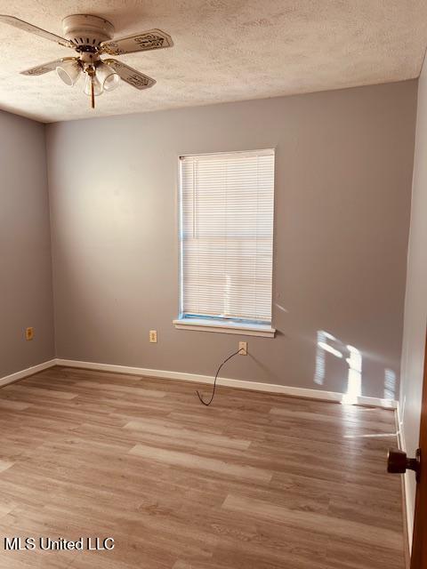 unfurnished room with a textured ceiling, a ceiling fan, and wood finished floors