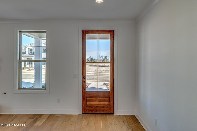 doorway with light hardwood / wood-style floors, plenty of natural light, and crown molding