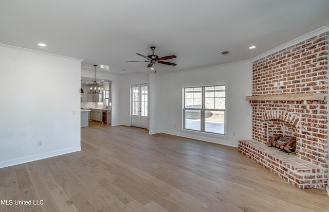 unfurnished living room featuring ceiling fan with notable chandelier, light hardwood / wood-style flooring, crown molding, and a fireplace