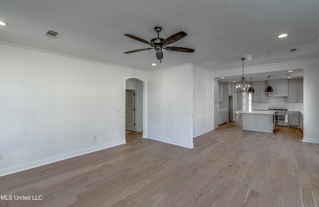 unfurnished living room with ceiling fan with notable chandelier, crown molding, and light wood-type flooring