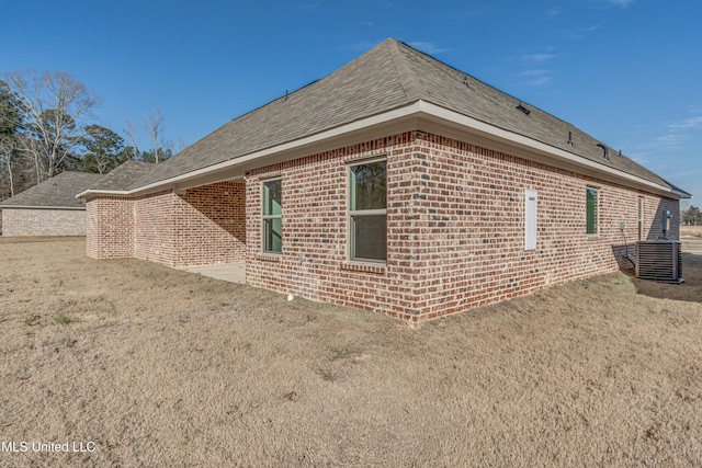 view of side of property featuring central AC and a yard