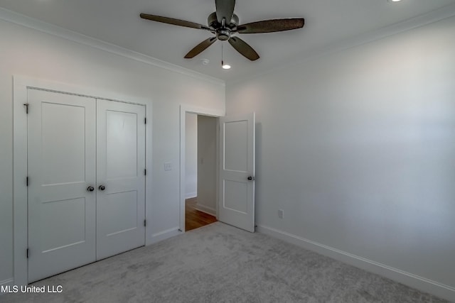 unfurnished bedroom featuring ceiling fan, a closet, light carpet, and ornamental molding