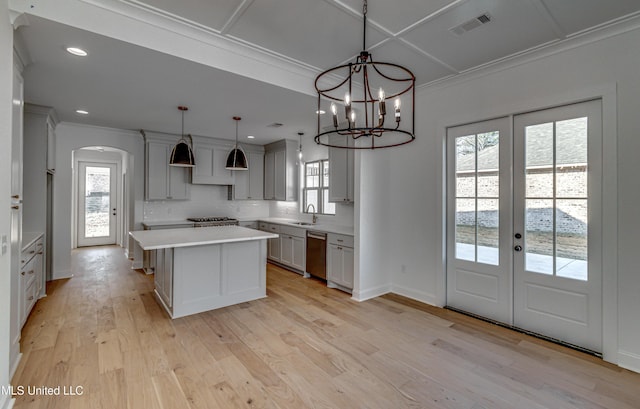 kitchen with a wealth of natural light, dishwasher, a kitchen island, decorative light fixtures, and light wood-type flooring