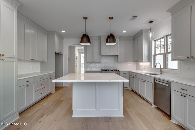 kitchen with light wood-type flooring, dishwasher, a center island, and decorative light fixtures