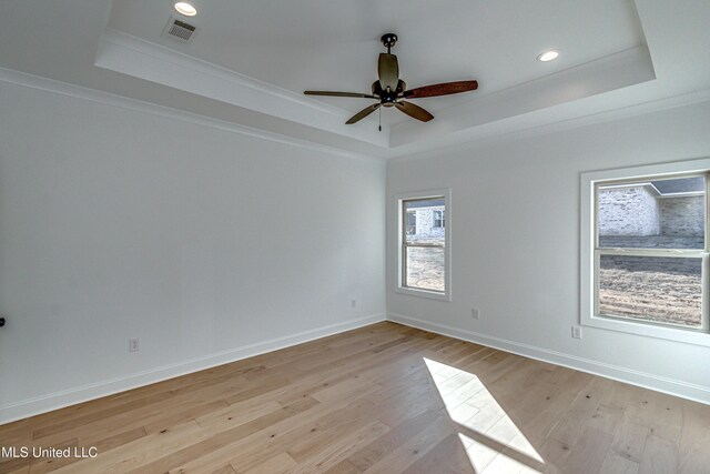 unfurnished room with crown molding, a raised ceiling, and light wood-type flooring