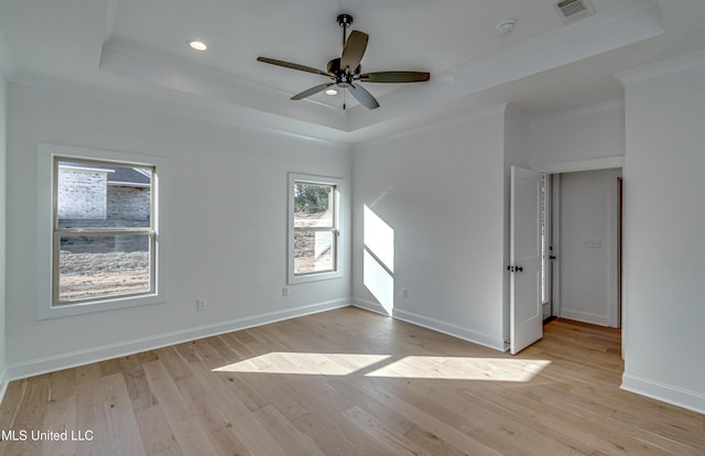 spare room featuring crown molding, light hardwood / wood-style floors, ceiling fan, and a tray ceiling