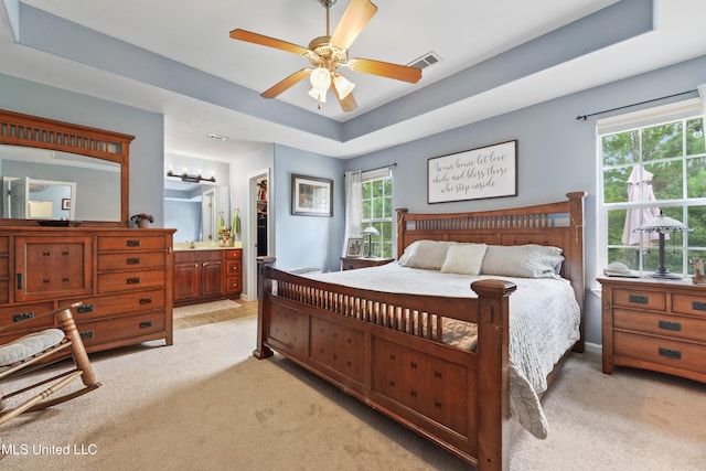 2301 Paula Cir, Ocean Springs, MS 39564 - bedroom featuring light colored carpet, connected bathroom, a tray ceiling, a ceiling fan, and a walk in closet