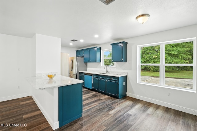 611 E E Lakeshore Dr, Carriere, MS 39426 - kitchen featuring blue cabinetry, freestanding refrigerator, dishwashing machine, dark wood-style flooring, and a peninsula
