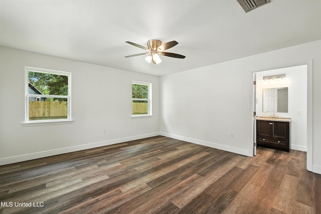 611 E E Lakeshore Dr, Carriere, MS 39426 - unfurnished bedroom featuring multiple windows, dark wood finished floors, ensuite bathroom, and a ceiling fan