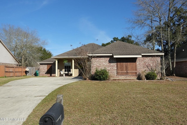 rear view of house with roof with shingles, brick siding, a lawn, and fence