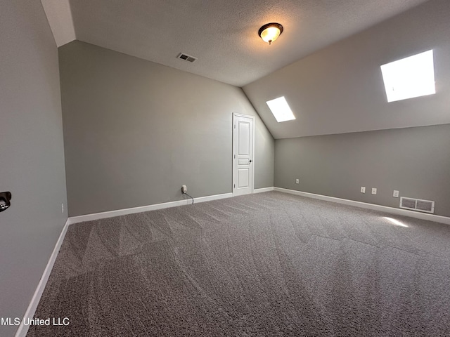 bonus room with a textured ceiling, lofted ceiling with skylight, and carpet floors