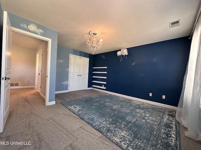 interior space with carpet, a closet, a textured ceiling, and an inviting chandelier