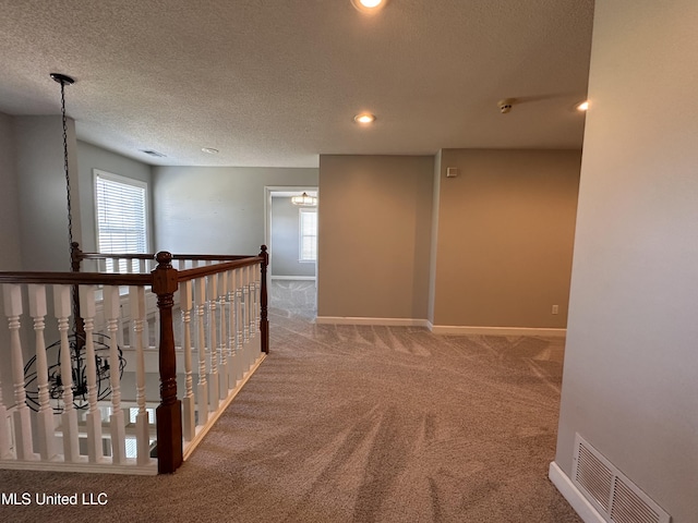 hallway with carpet, a textured ceiling, and a wealth of natural light