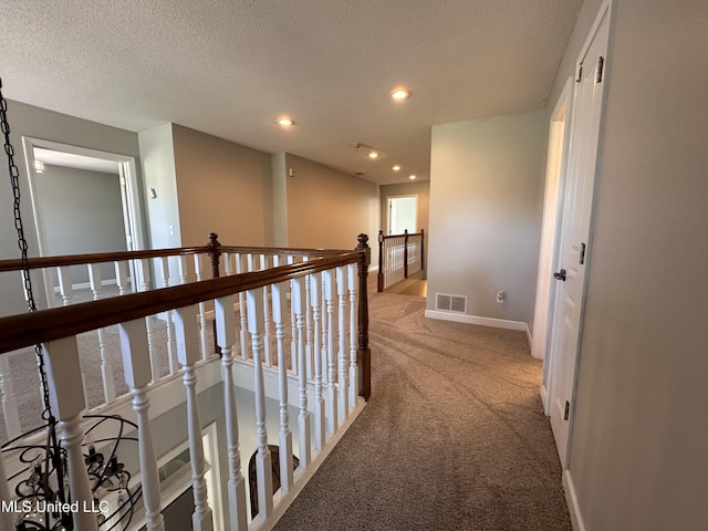 hallway featuring carpet and a textured ceiling