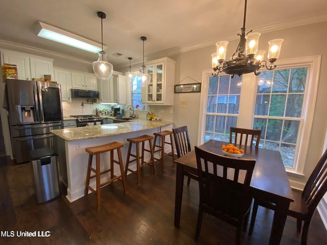 dining area featuring sink, crown molding, dark wood-type flooring, and an inviting chandelier