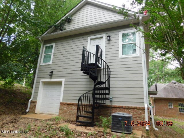 rear view of house featuring cooling unit and a garage