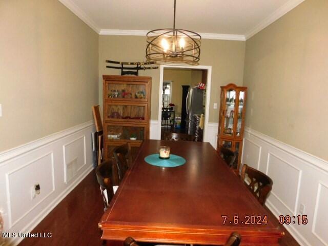 dining room with hardwood / wood-style flooring, ornamental molding, and a chandelier