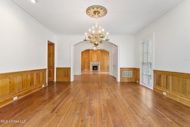 unfurnished living room featuring crown molding, hardwood / wood-style floors, and an inviting chandelier