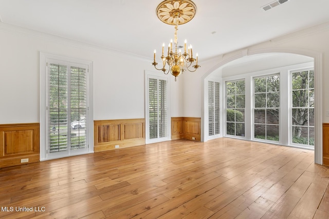 unfurnished living room featuring light hardwood / wood-style floors, crown molding, and an inviting chandelier