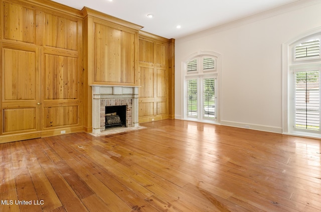 unfurnished living room featuring ornamental molding, light wood-type flooring, and a brick fireplace