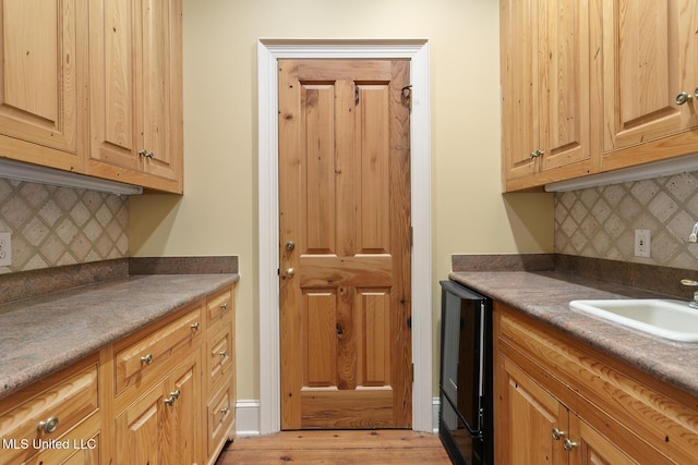 kitchen featuring decorative backsplash, light wood-type flooring, wine cooler, and sink