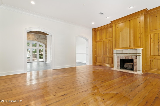 unfurnished living room with a fireplace, light hardwood / wood-style floors, and ornamental molding