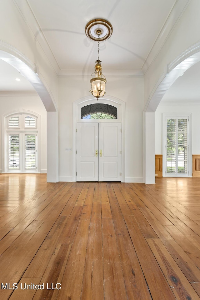 entrance foyer featuring hardwood / wood-style flooring, a notable chandelier, a healthy amount of sunlight, and crown molding