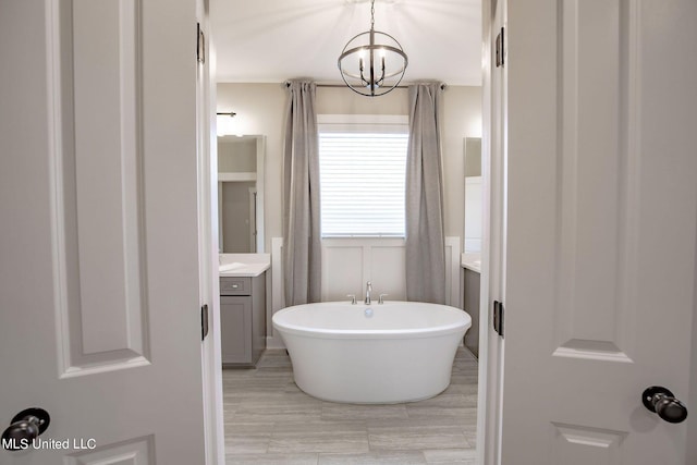 bathroom featuring vanity, a bath, and a chandelier