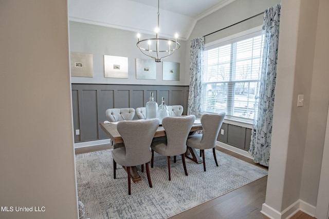 dining area featuring a healthy amount of sunlight, lofted ceiling, a notable chandelier, and hardwood / wood-style floors