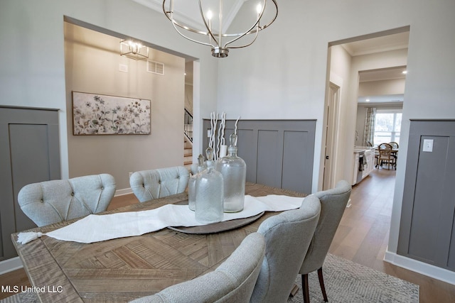 dining space featuring hardwood / wood-style flooring, ornamental molding, and a chandelier