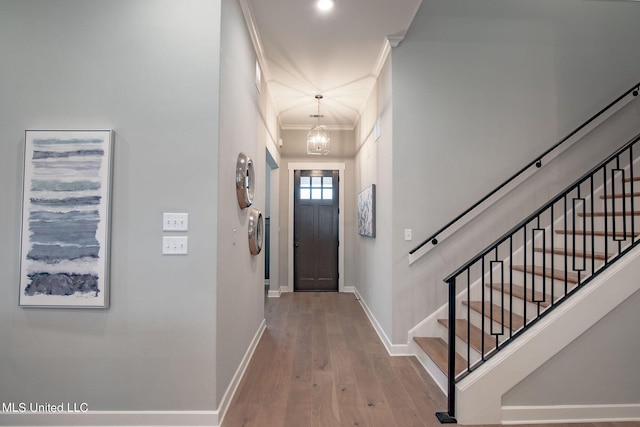 entrance foyer featuring crown molding, a notable chandelier, and light wood-type flooring