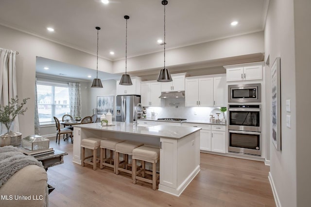 kitchen with white cabinetry, a kitchen island with sink, pendant lighting, and appliances with stainless steel finishes