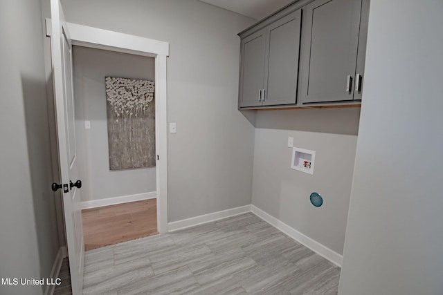 laundry area featuring washer hookup, light hardwood / wood-style floors, and cabinets