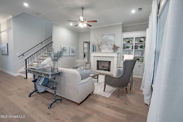 living room with ceiling fan, crown molding, and light hardwood / wood-style flooring