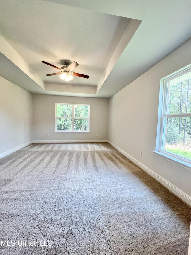 15693 Perdido Dr, Gulfport, MS 39503 - carpeted empty room featuring baseboards, a ceiling fan, a tray ceiling, and a healthy amount of sunlight
