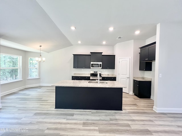 15693 Perdido Dr, Gulfport, MS 39503 - kitchen with an island with sink, dark cabinetry, a sink, stainless steel microwave, and a chandelier