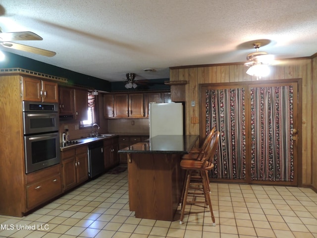 kitchen with dishwashing machine, a textured ceiling, a kitchen bar, double oven, and refrigerator