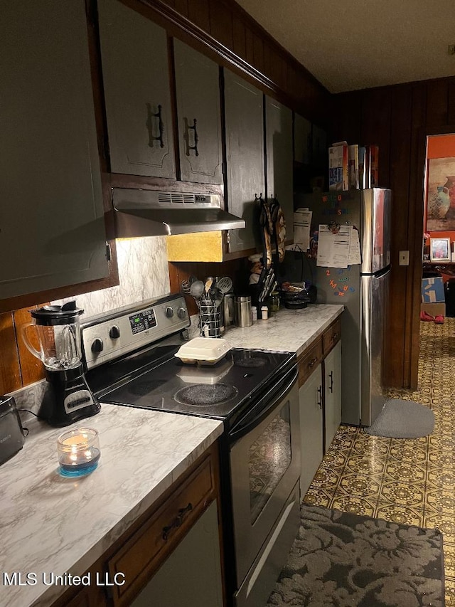 kitchen with dark brown cabinets, stainless steel appliances, and wooden walls