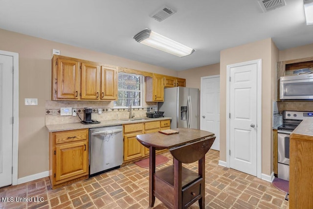 kitchen featuring stainless steel appliances, light countertops, a sink, and visible vents