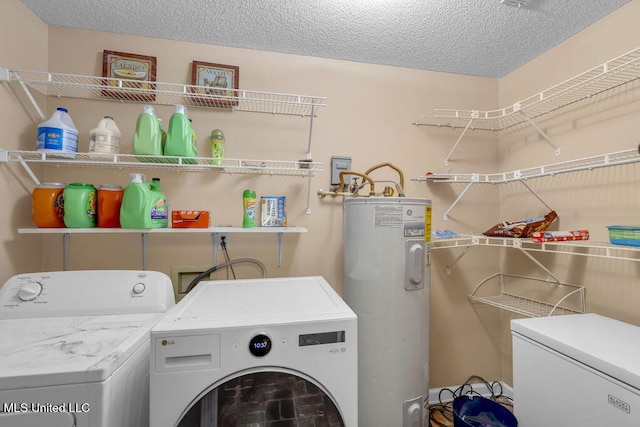 clothes washing area with laundry area, water heater, washer and clothes dryer, and a textured ceiling