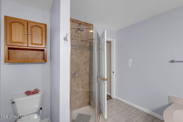 bathroom with a stall shower, baseboards, toilet, and tile patterned floors