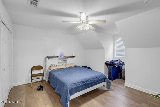 bedroom with lofted ceiling, a closet, visible vents, and wood finished floors