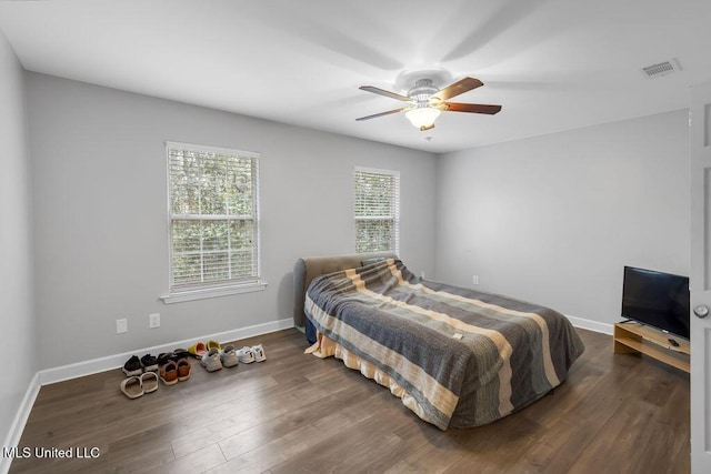 bedroom with a ceiling fan, dark wood-style flooring, visible vents, and baseboards