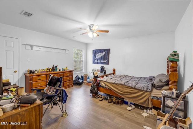 bedroom featuring wood finished floors, visible vents, and a ceiling fan