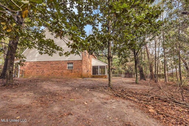 view of home's exterior featuring brick siding and a sunroom