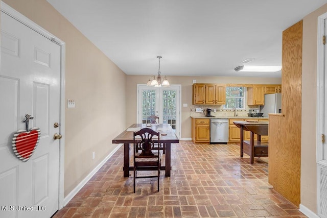 dining area featuring brick floor, a notable chandelier, and baseboards