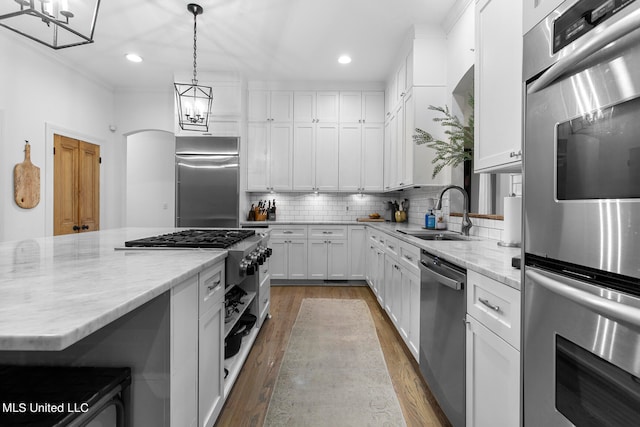 kitchen featuring high end appliances, white cabinetry, light hardwood / wood-style flooring, and pendant lighting