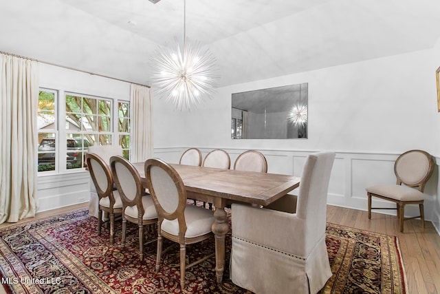 dining space with a notable chandelier, wood-type flooring, and lofted ceiling